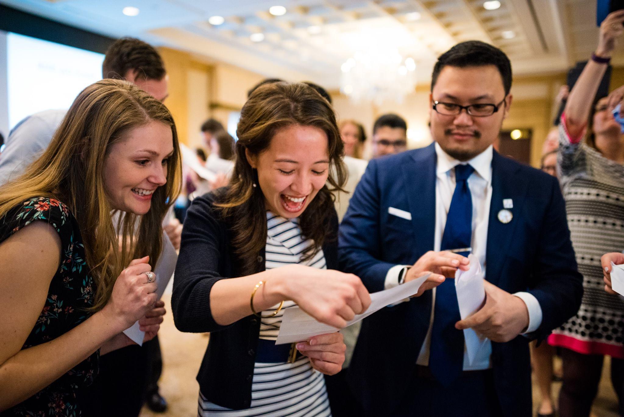 Student happily reads her match day letter with friends looking on.